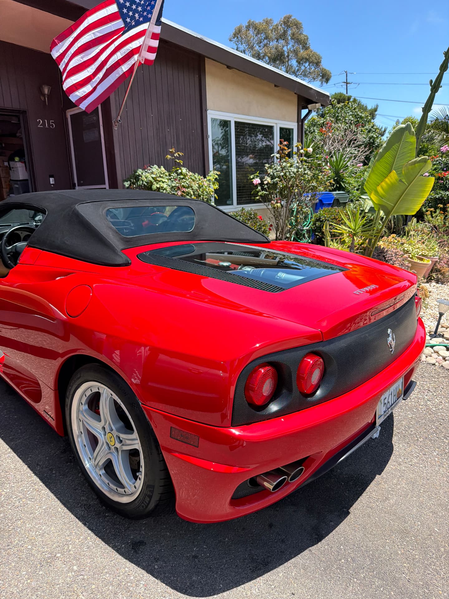 Red Ferrari convertible with a polished finish parked in a residential driveway